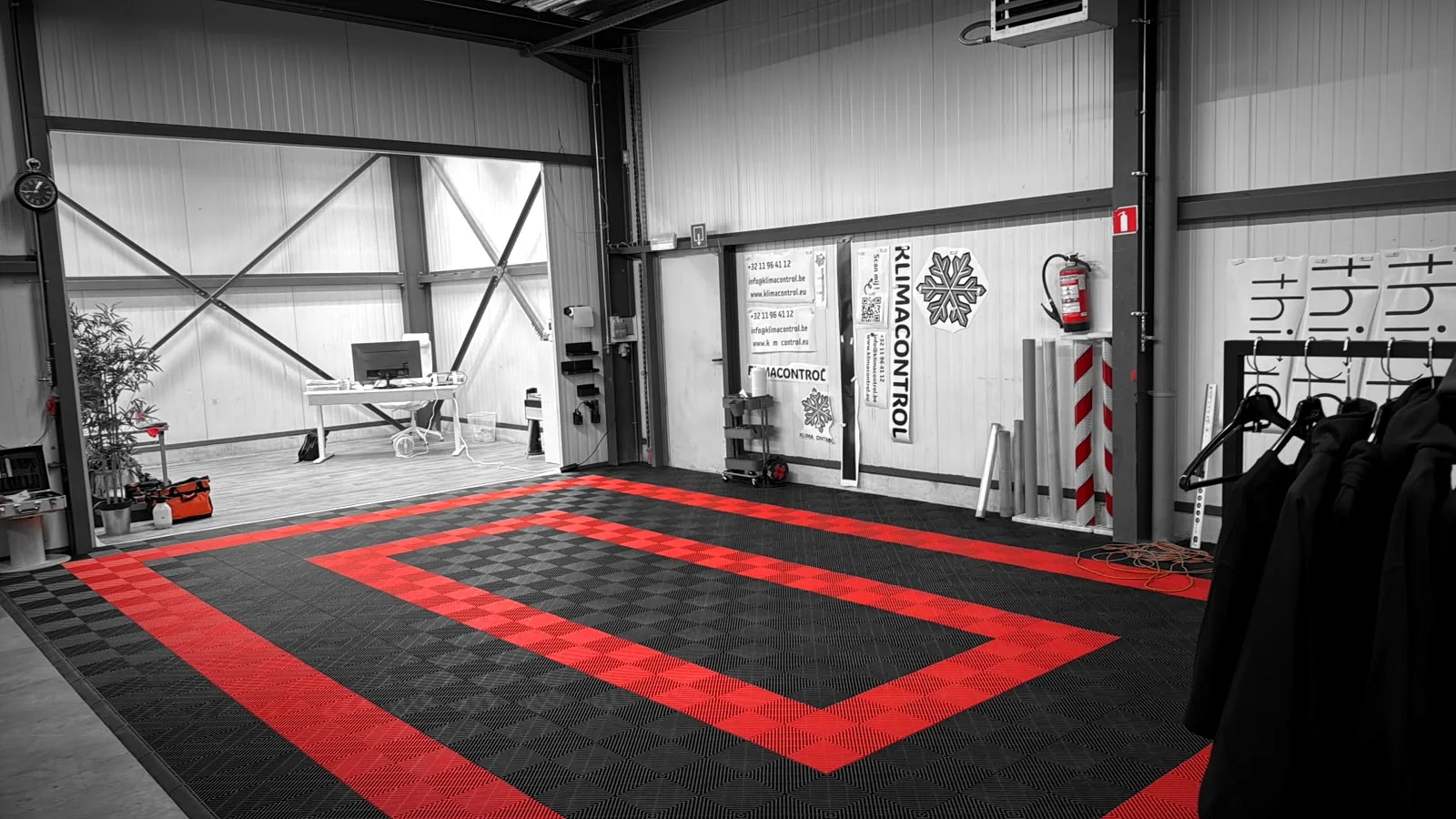 Ons atelier in Heusden-Zolder, met de rood-zwarte werkvloer waar we wagens beletteren